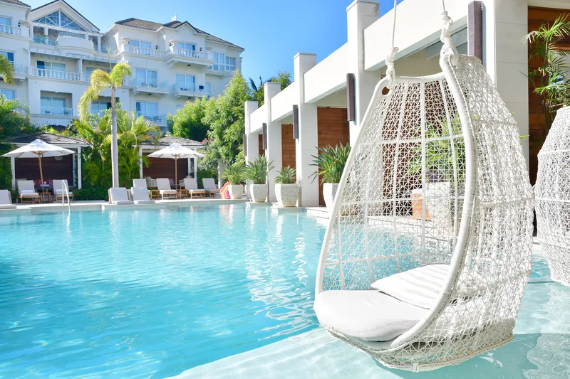 Une piscine du resort, fauteuils suspendus au bord de l'eau