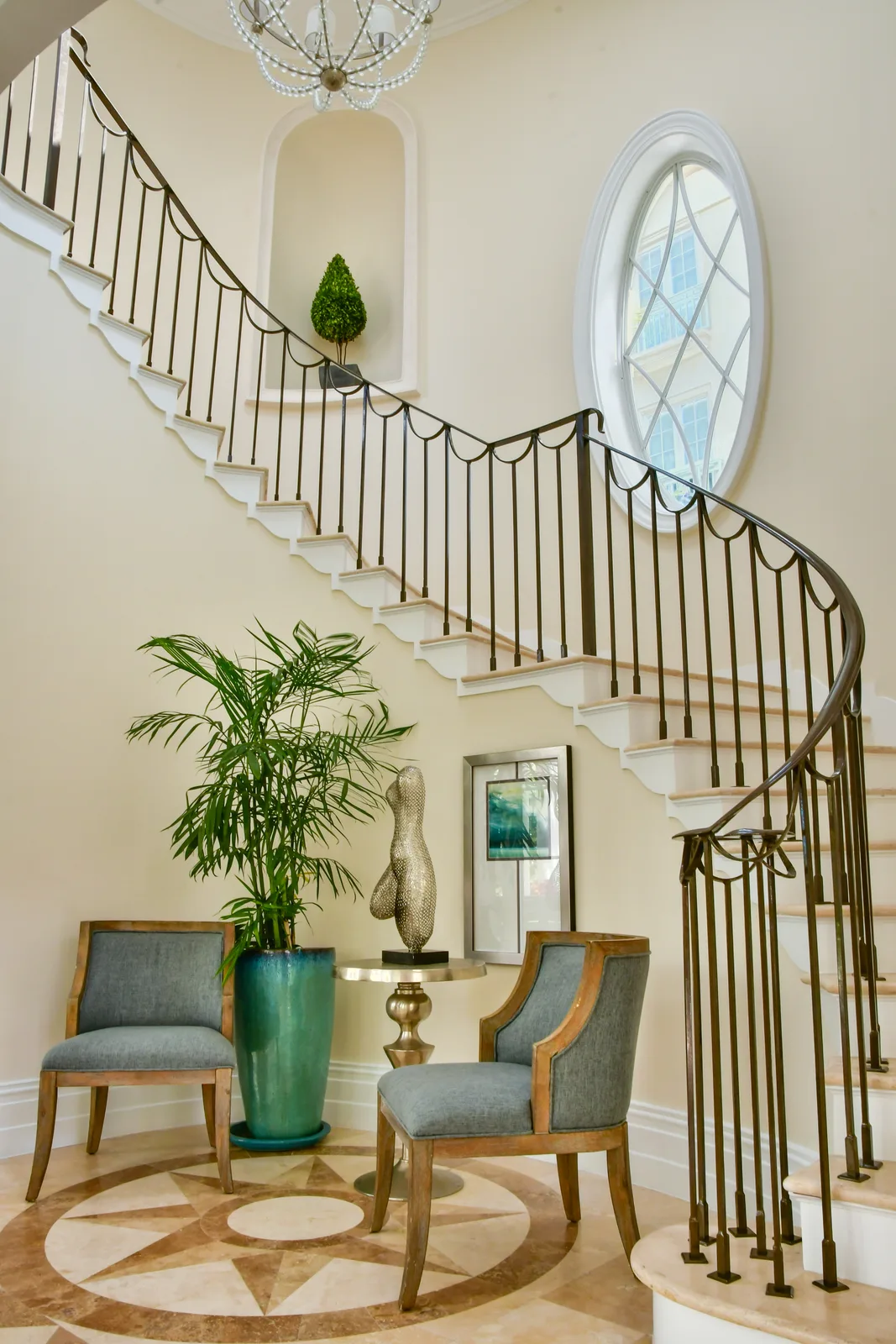 L'escalier et sa rampe en fer forgé sous une fenêtre ovale