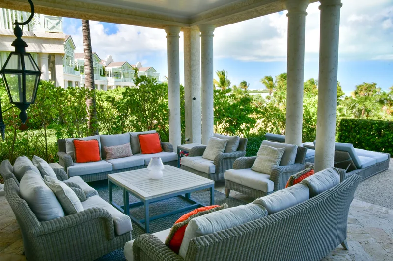 La terrasse couverte et son salon en rotin, le jardin au-delà