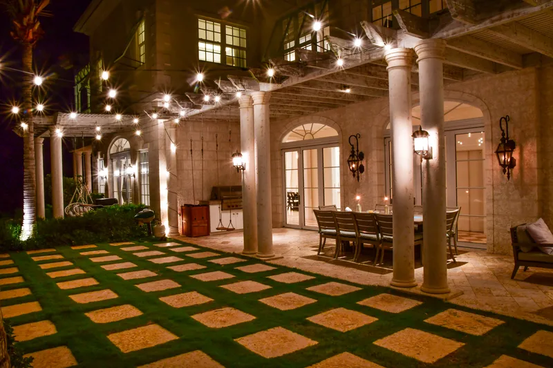La cour la nuit, guirlandes lumineuses au-dessus de la pelouse et de la table extérieure