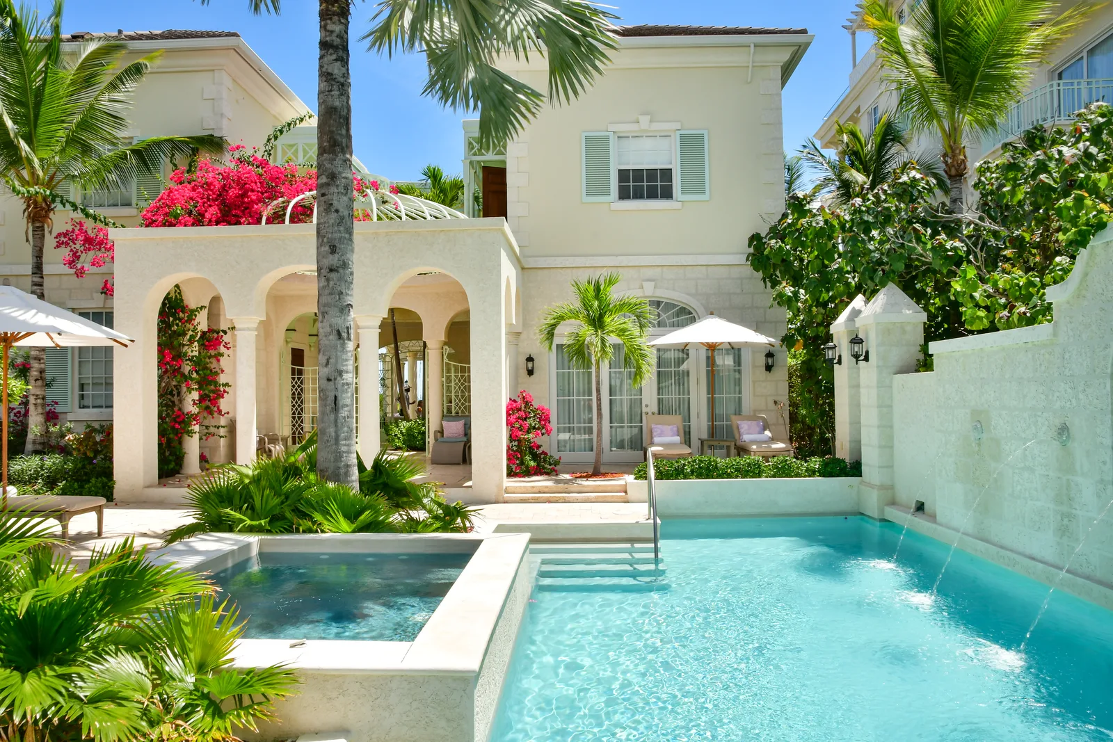La piscine à débordement privée de Villa One, la maison et ses palmiers derrière